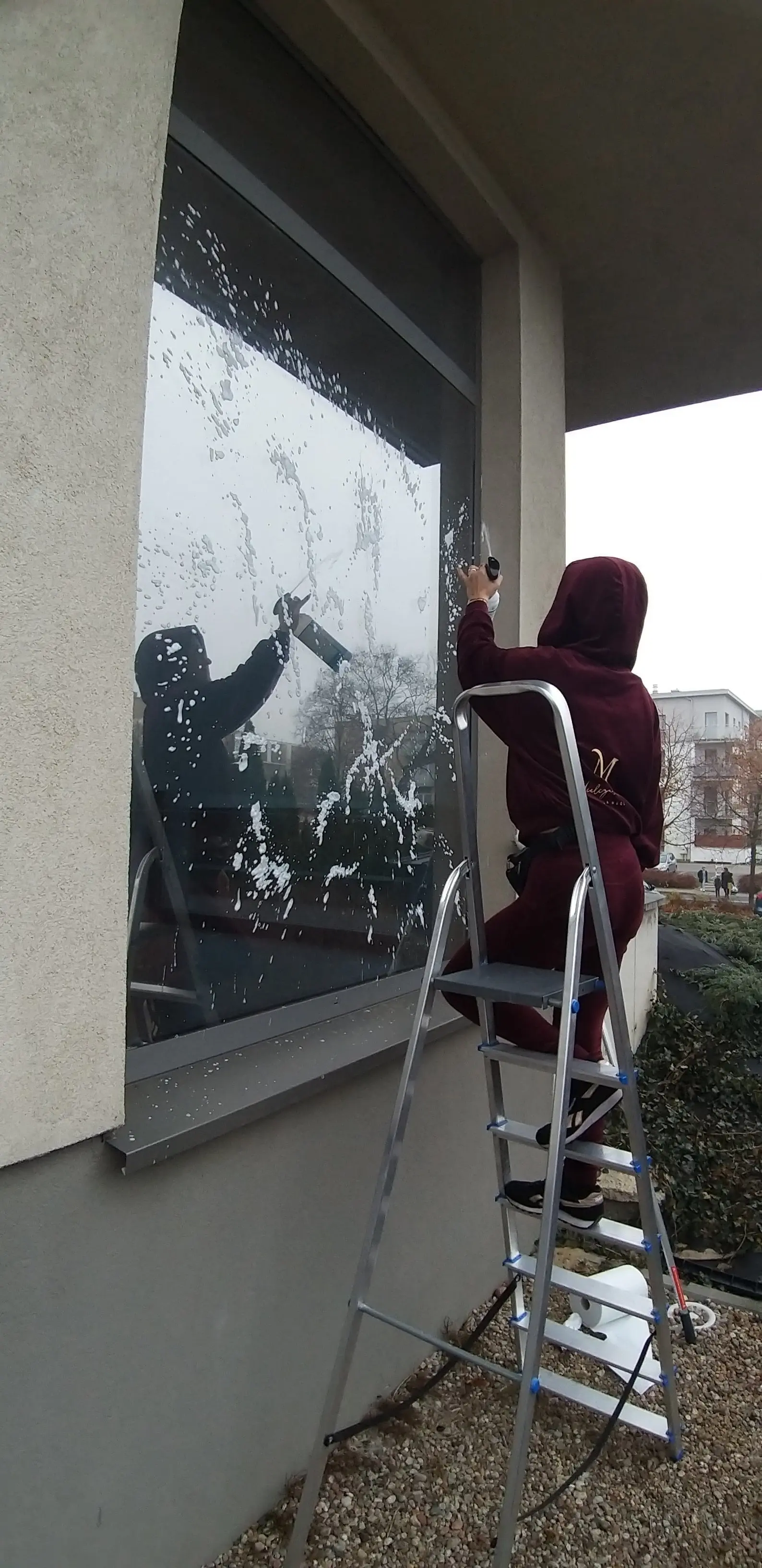 Sprzątaczka myjąca okno na zewnątrz budynku – profesjonalne mycie okien zewnętrznych przez Karen Błysk